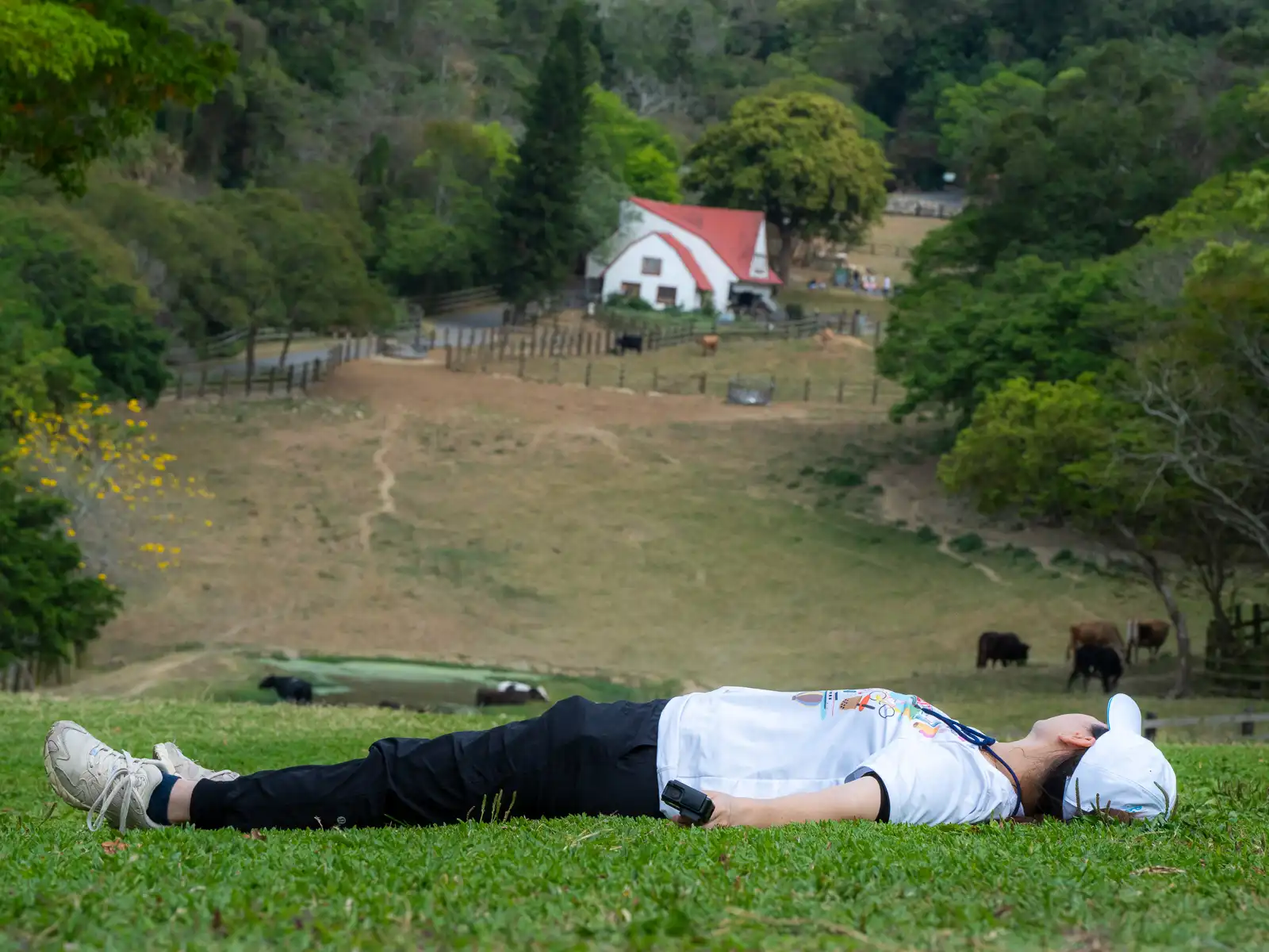 A tourist is lying down on a large grassy field.