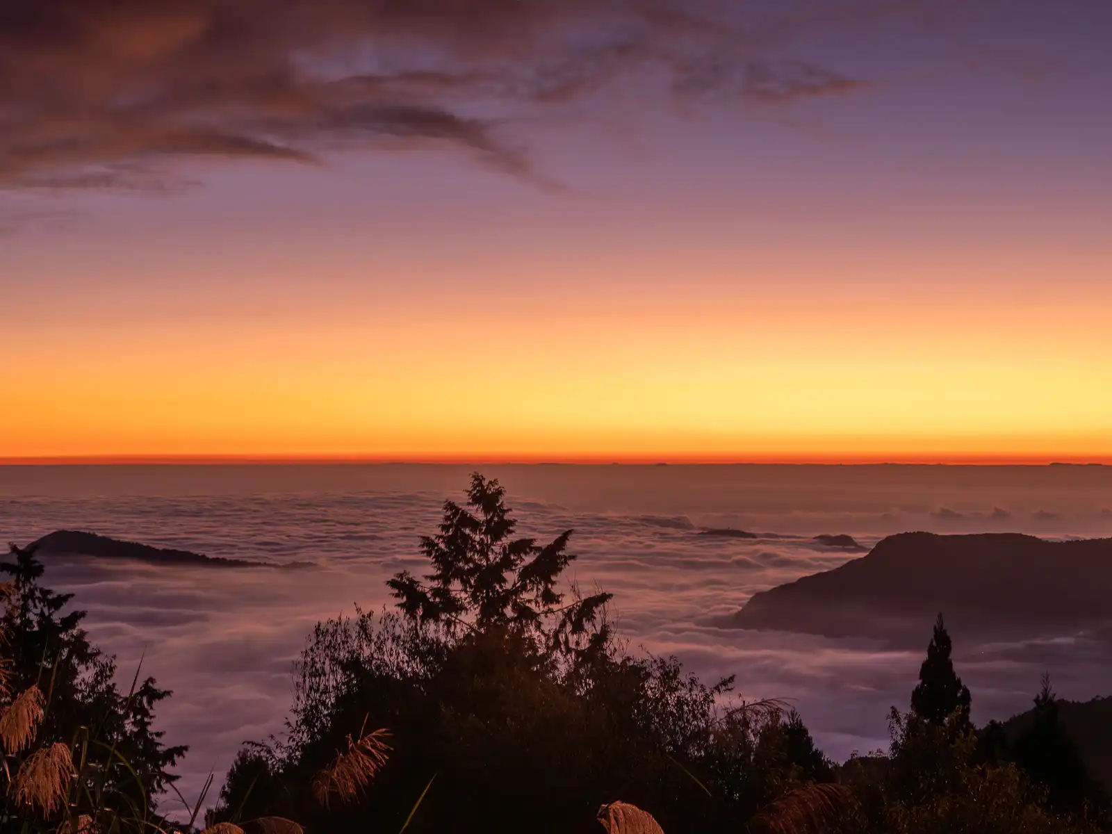 Some mountain peaks are visible poking through a sea of clouds.