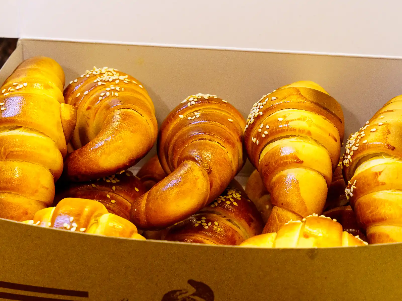 A container is filled with about a dozen croissants.