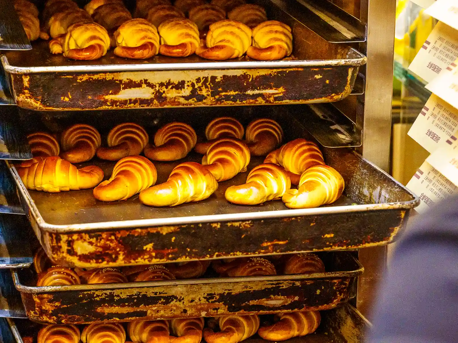 A cart is filled with trays of freshly-baked croissants.