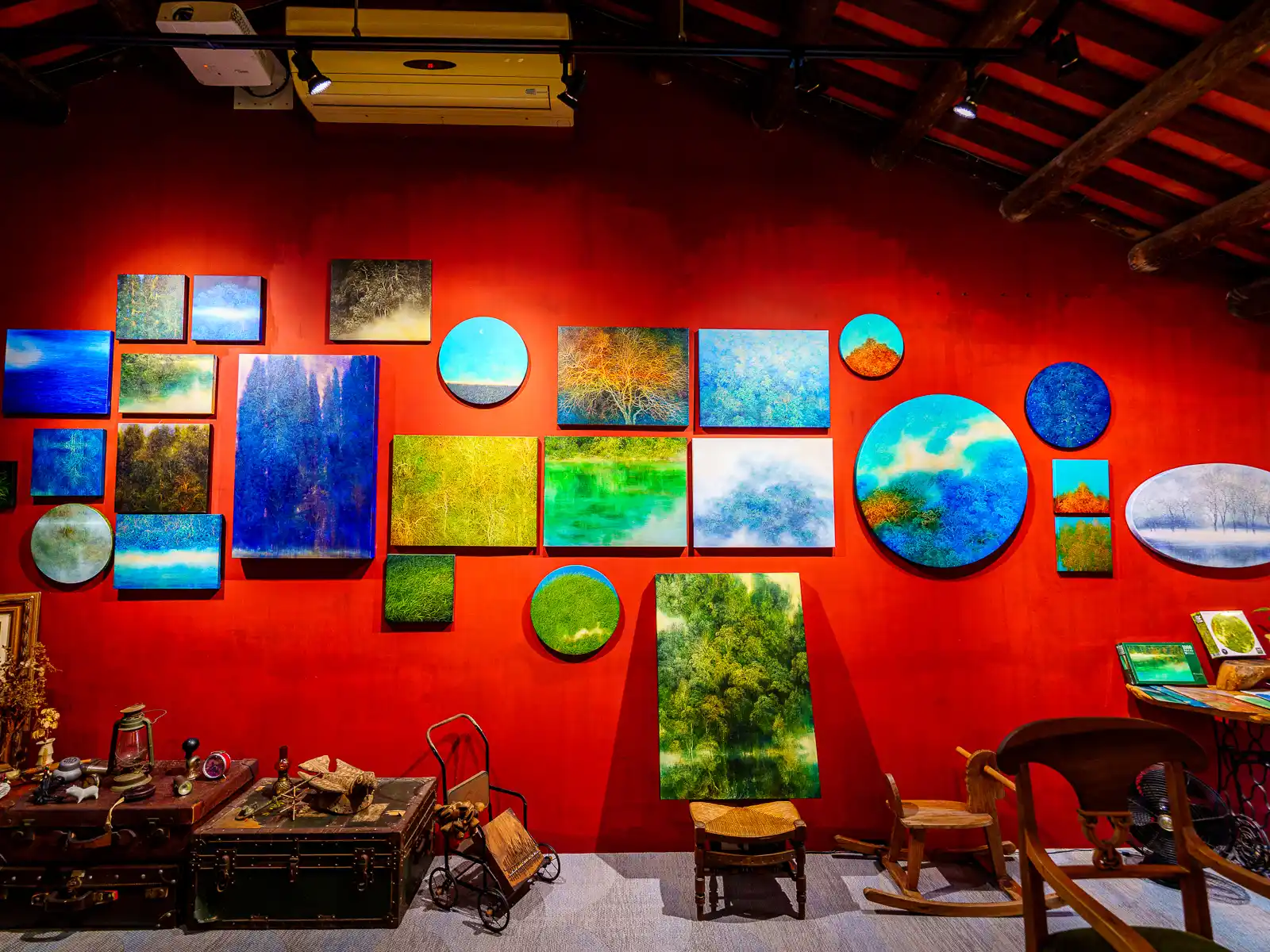 Paintings are on display against a bright red colored wall in the Su Chiung Art Museum.