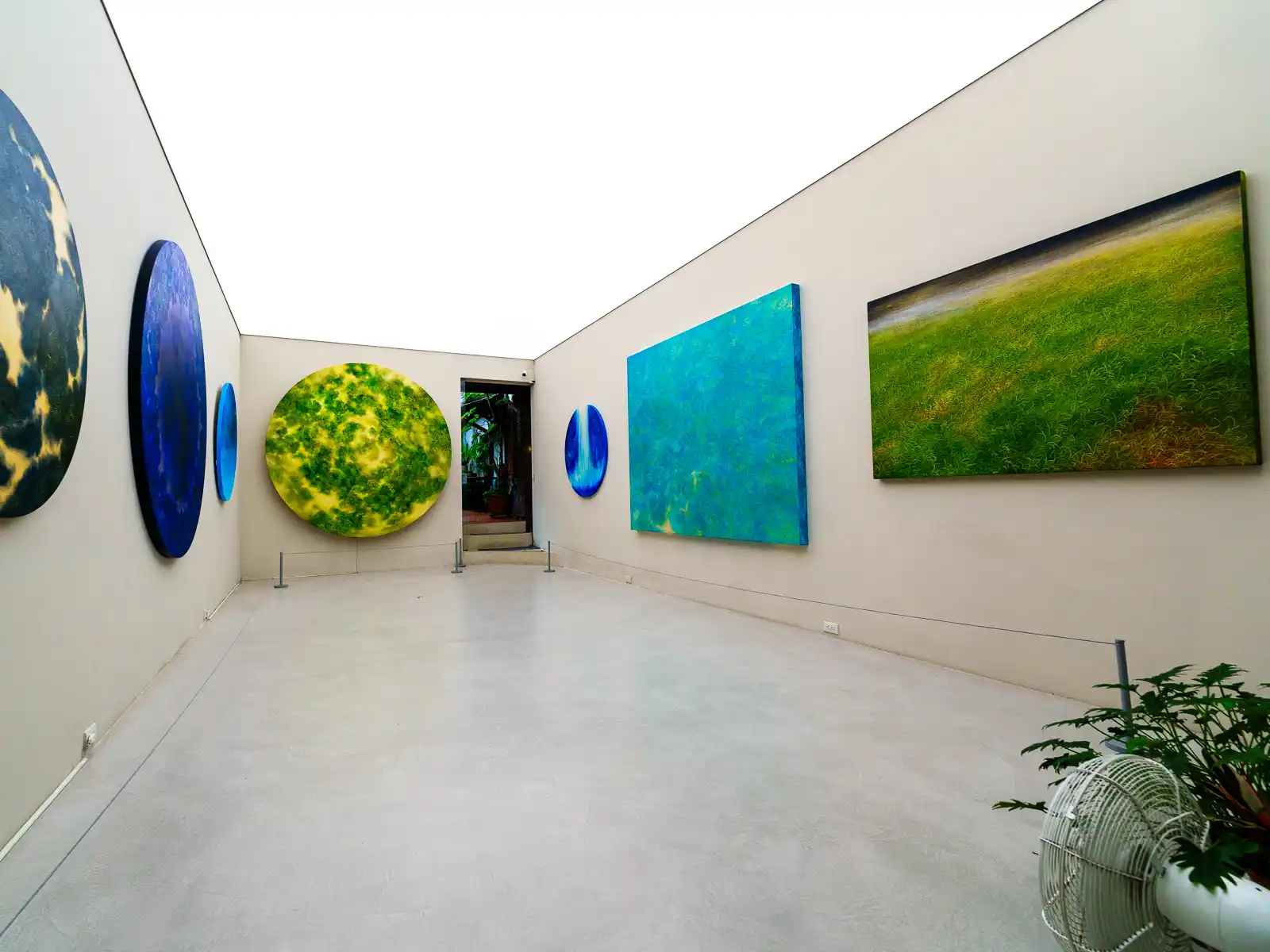 Several colorful paintings hang on the walls in this long white-walled room at Su Chiang Art Museum.