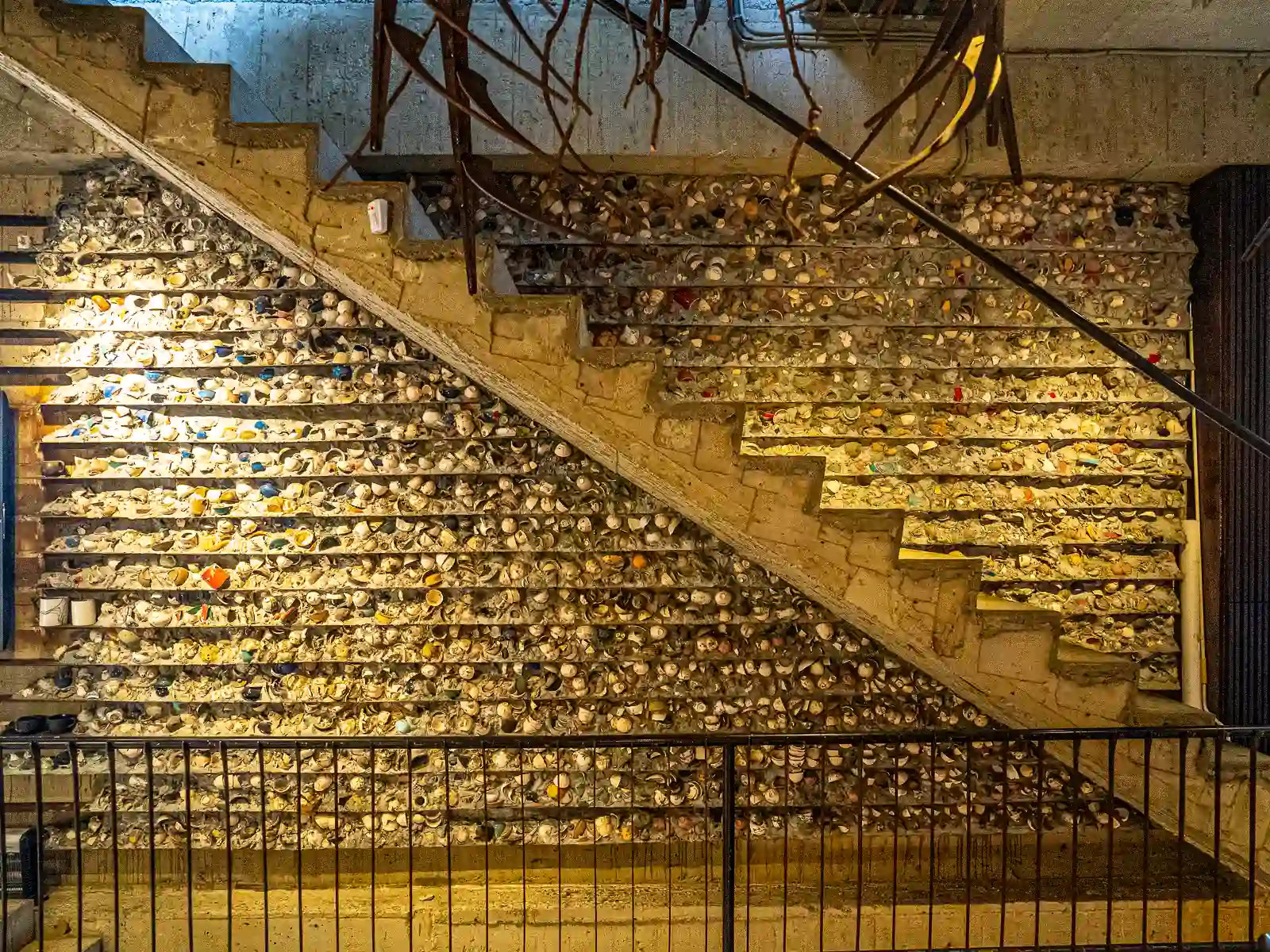 A wall made from clay has been decorated with broken pieces of pottery that have been embedded into the wall.