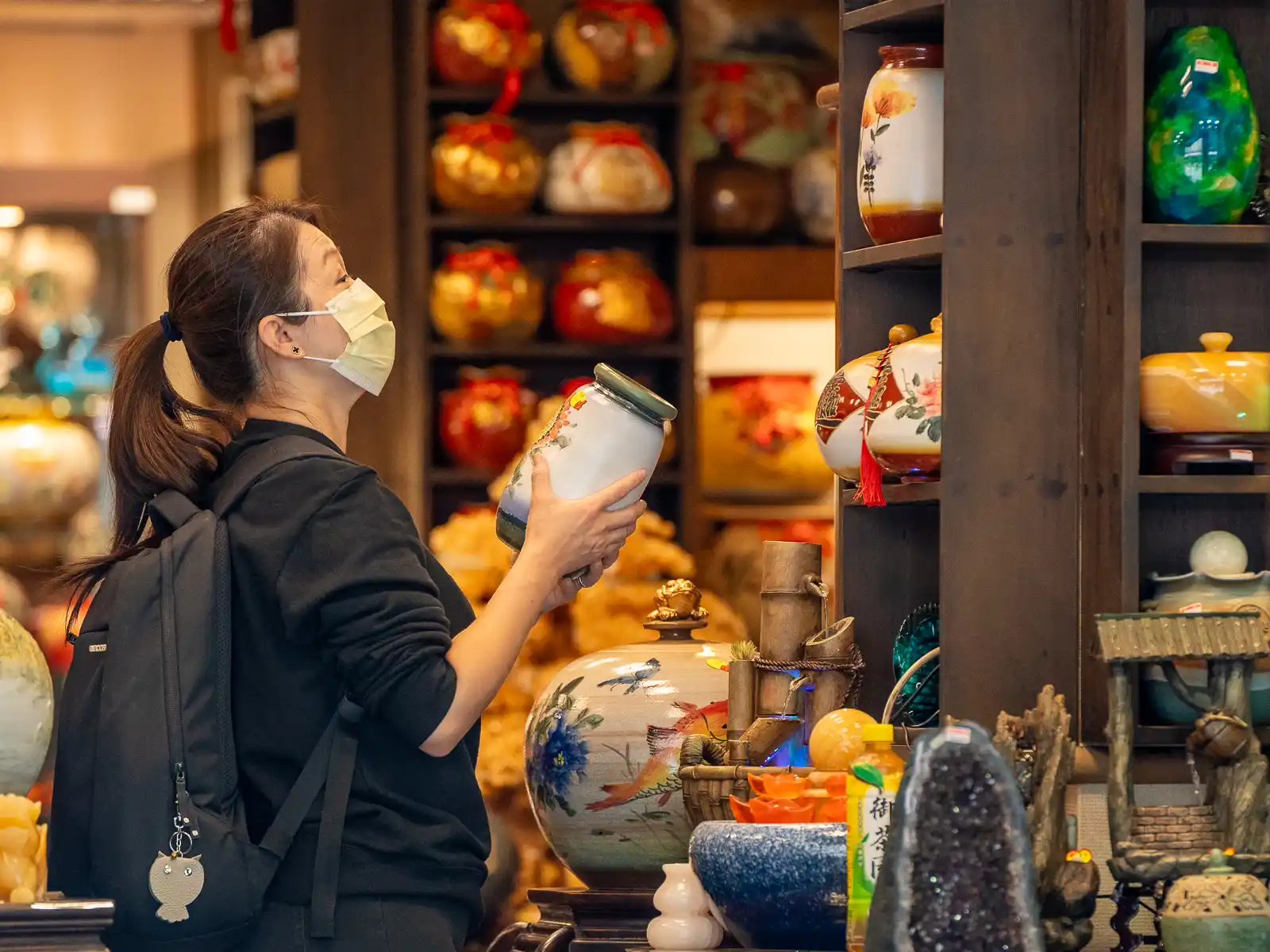 A tourist examines a vase in a pottery shop in Yingge.