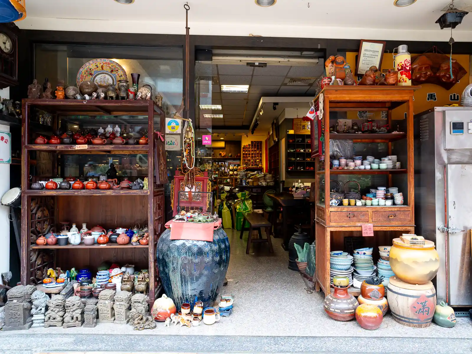 A more traditional ceramics shop is filled with pottery of all shapes and sizes; some teaware and stone carvings are also on display outside in front of the shop.