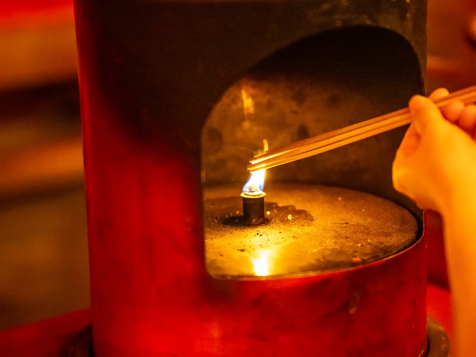 Sticks of incense are being lit over a candle.