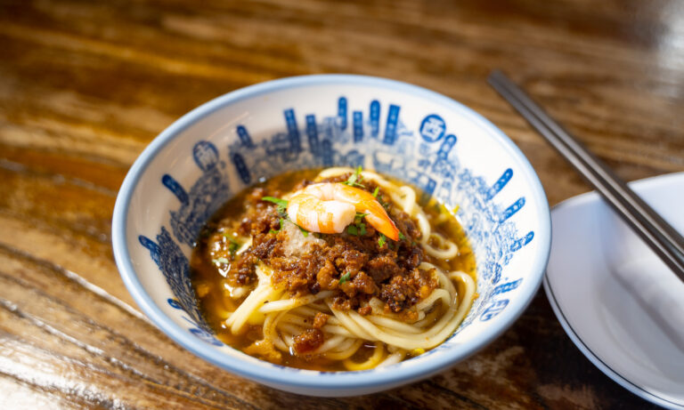 A bowl of Danzai Noodles topped with a shrimp.