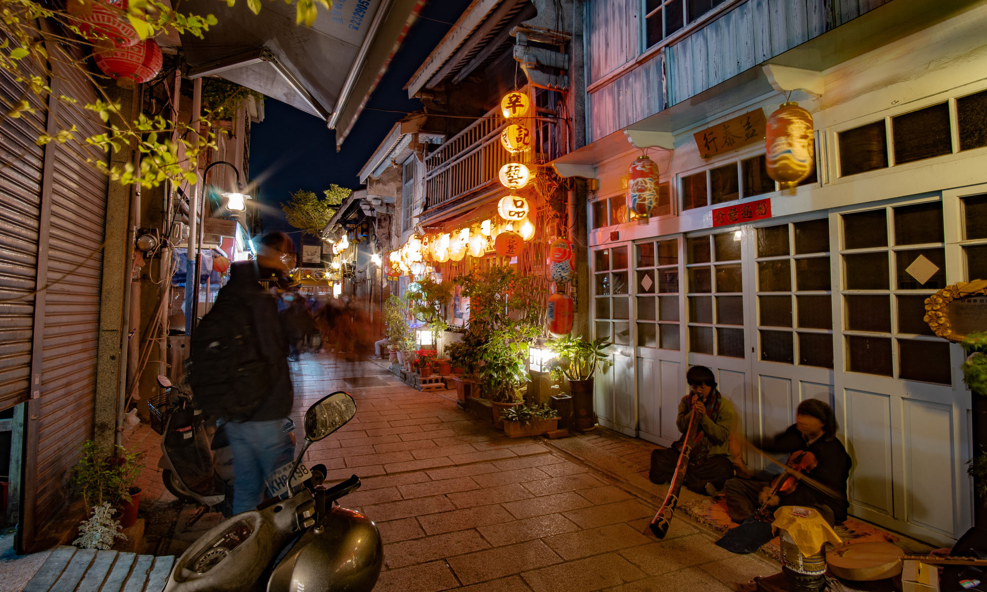 Buskers playing in a narrow alley at night.