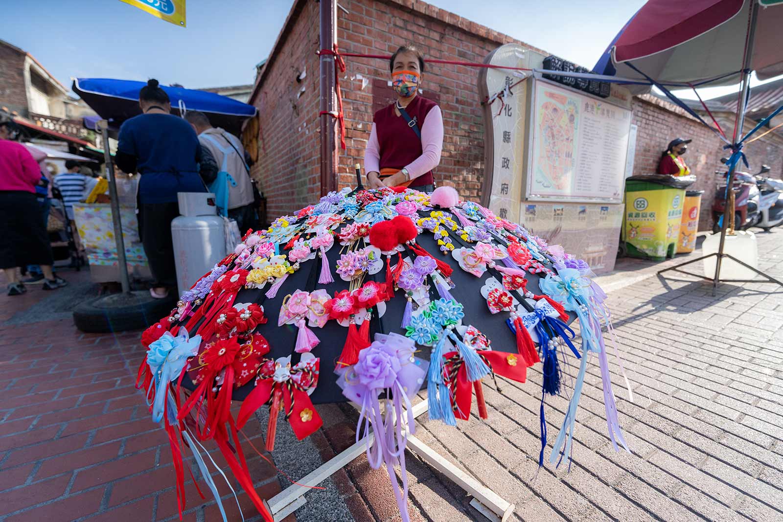 An umbrella covered in colorful pins on display on the side of Lukang Old Street.