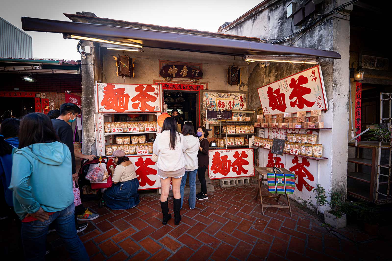 A small shop run out of someone's one-story home sells roasted wheat flour; the outside of the shop is adorned in white plaques with "roasted wheat flour" written in Chinese characters.