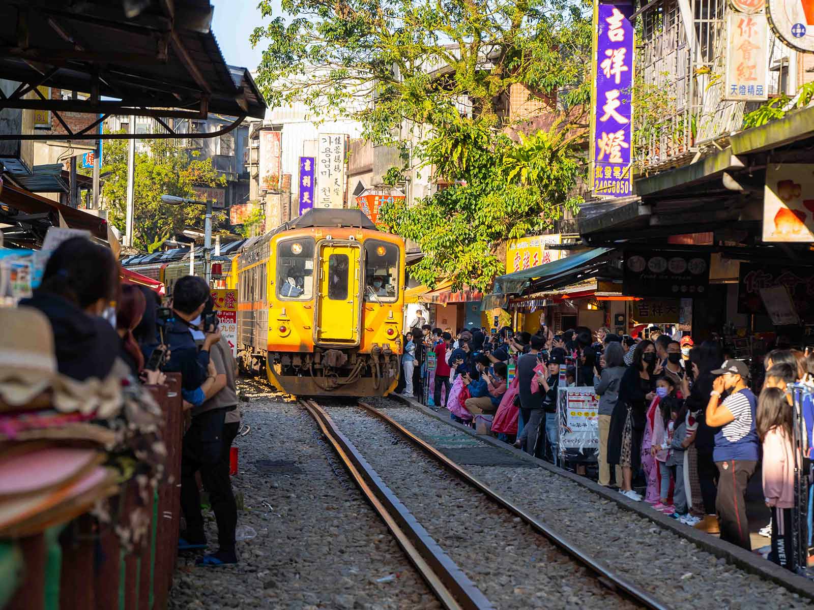 Crowds wait on either side of the track as a train passes through the narrow pedestrian area in Shifen Old Street.