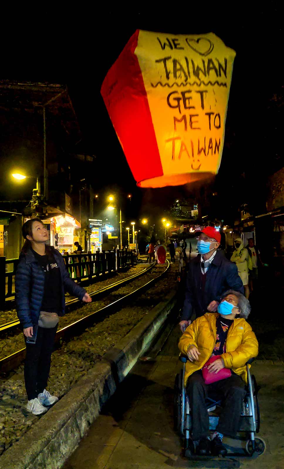 A family launches a sky lantern into the air at night.