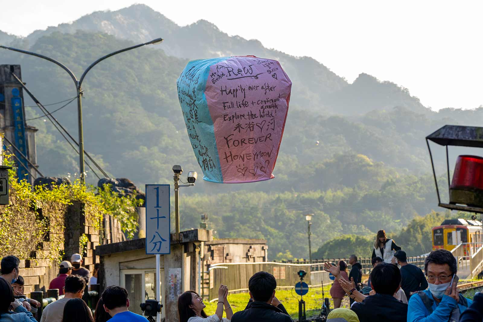 Just launched, a paper sky lantern floats above crowds of tourists in Shifen.