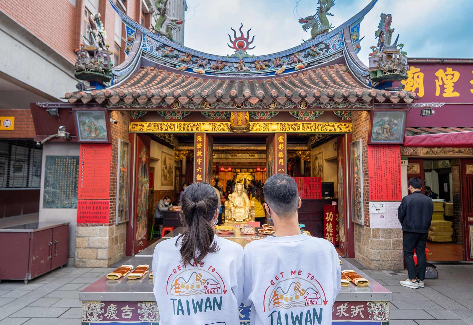 Two tourists appreciate the colorful facade of a narrow one-story temple on Dihua Old Street.