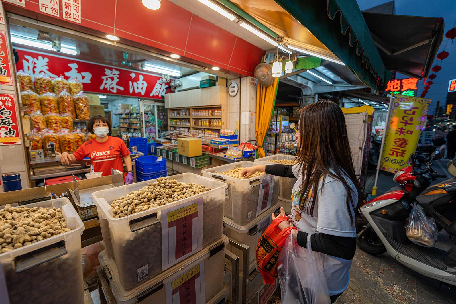 Cartons of peanuts for sale are piled outside of a shop specializing in sesame oil.