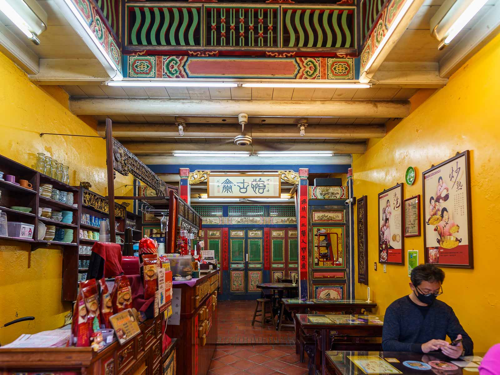 A cafe operates in a traditional house; the inside is long and narrow with colorful, elaborately painted details.