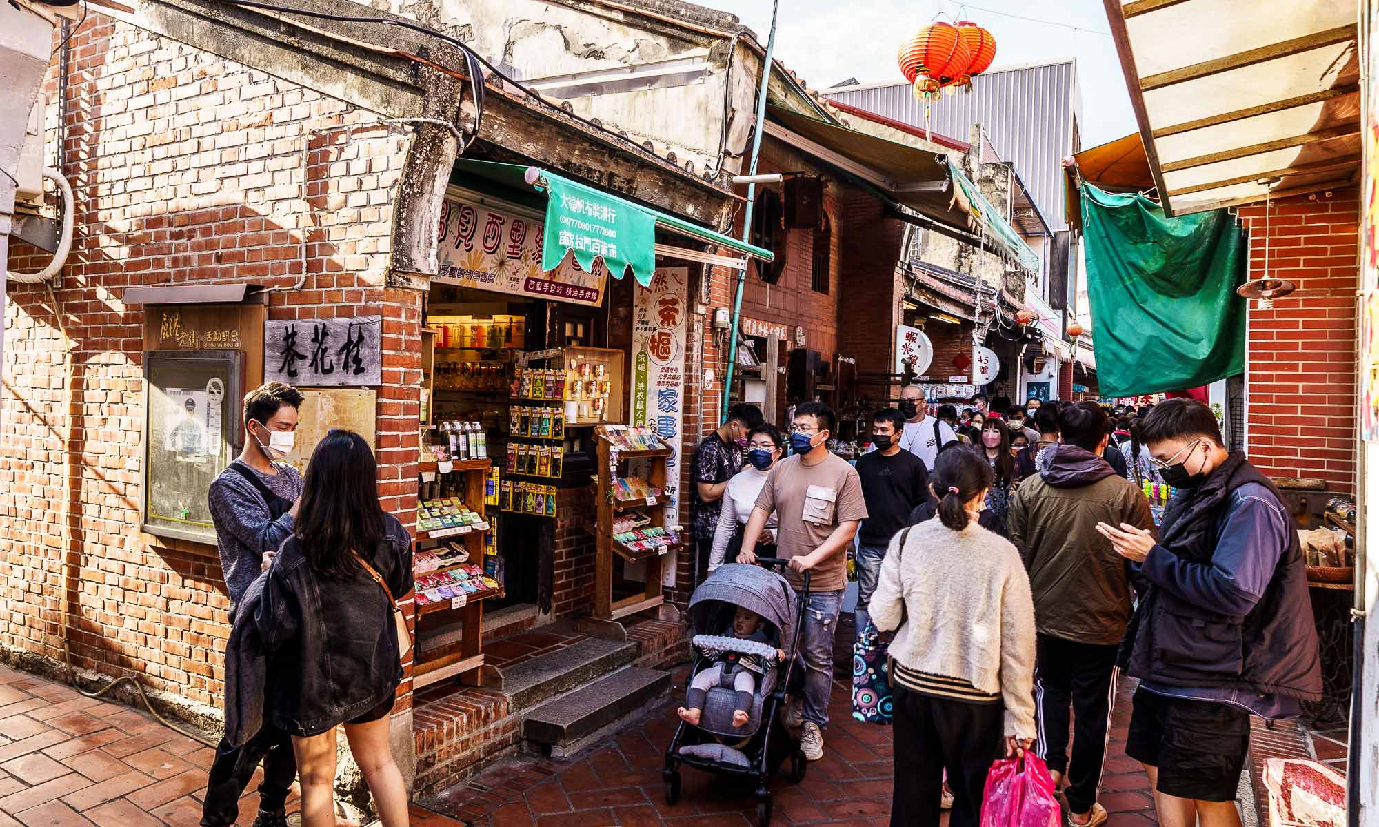 Crowds walk through a busy narrow alley made of red bricks in Lukang Old Street.