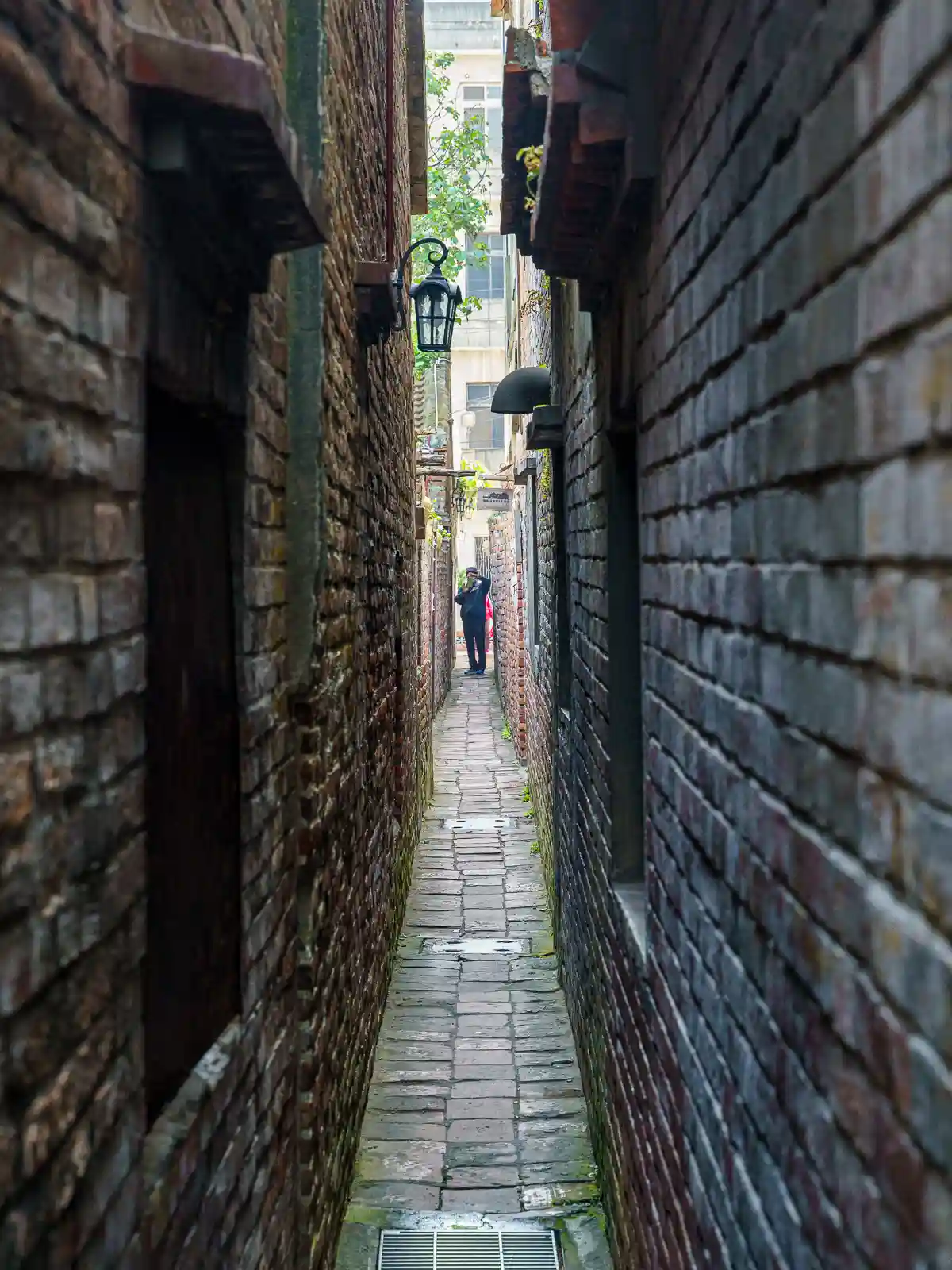 Looking down the narrow corridor of Gentlemen Lane we see a man taking a photo on the far side.