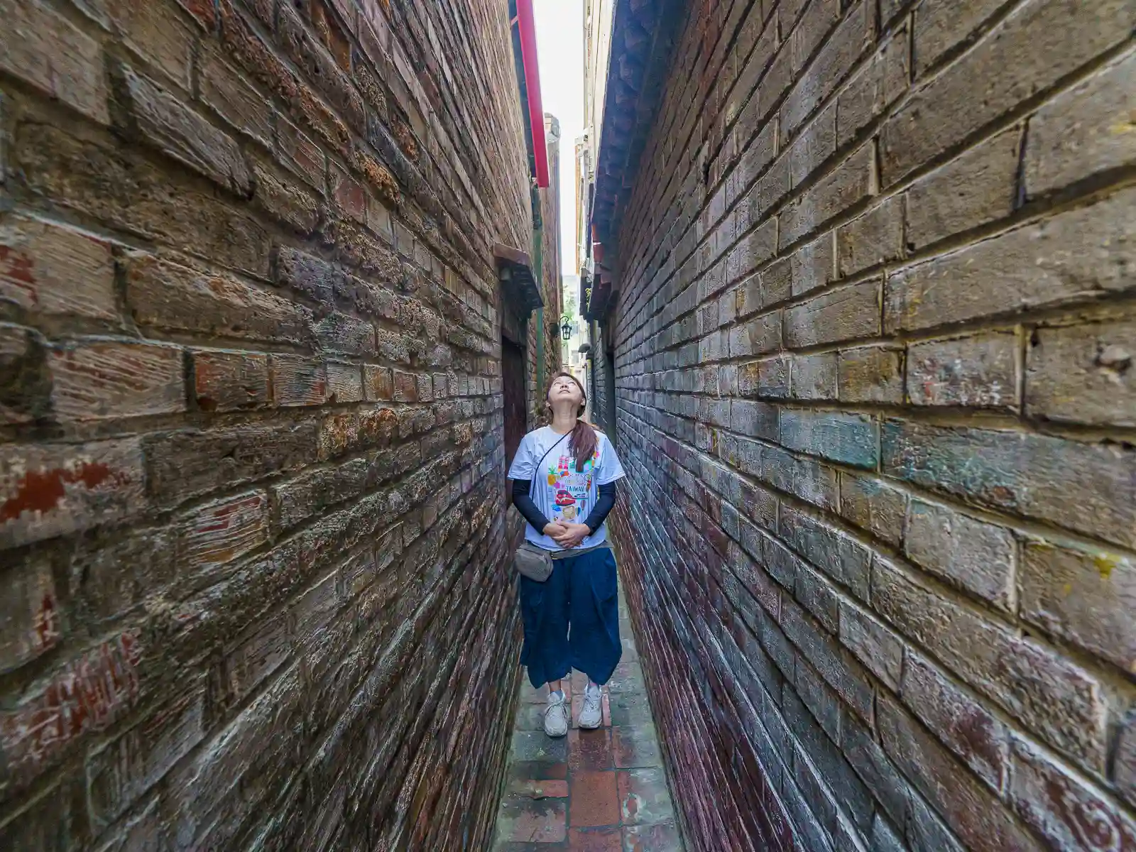 A tourist standing in Gentlemen Lane with her shoulders nearly touching the walls.