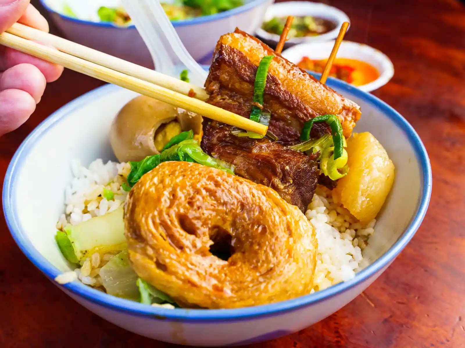 A bowl of rice is topped with juicy braised pork and gluten.