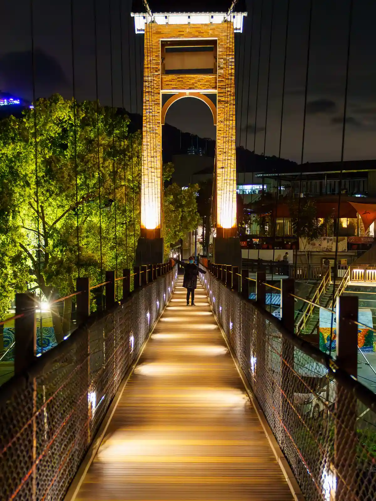 A tourist crosses Kangji Suspension Bridge at night.