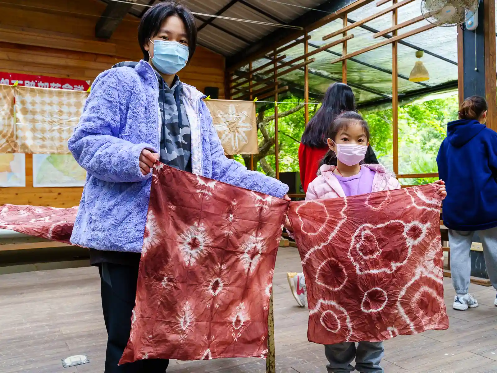 Two students hold up their tie-dyed works.