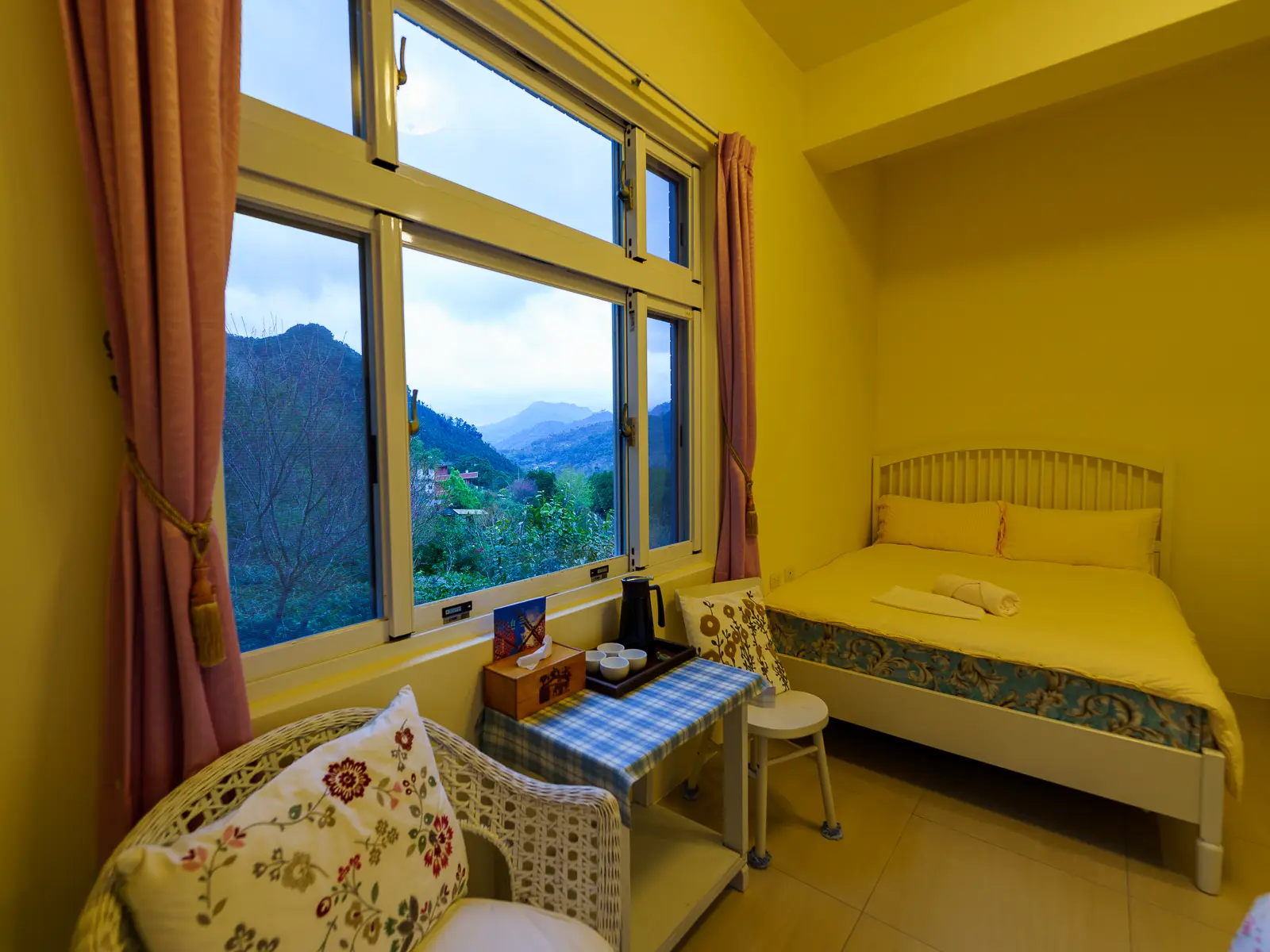 The interior view of a simple guest room with a mountain view.