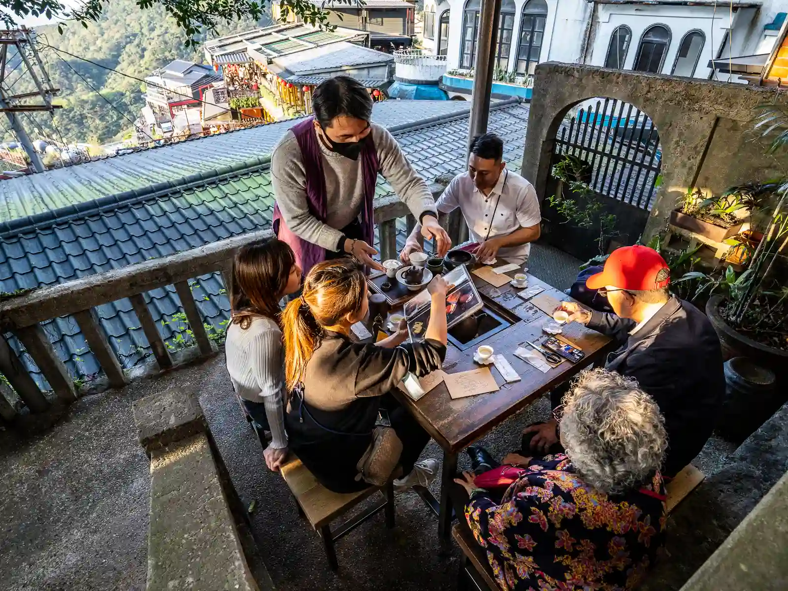 A group of guests brews tea in the outside seating area of Jiufen Tea House.