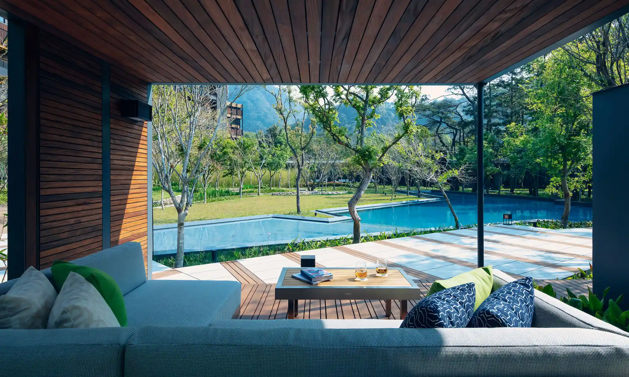 An outdoor poolside lounging area is surrounded by lush gardens at Hoshinoya Guguan.