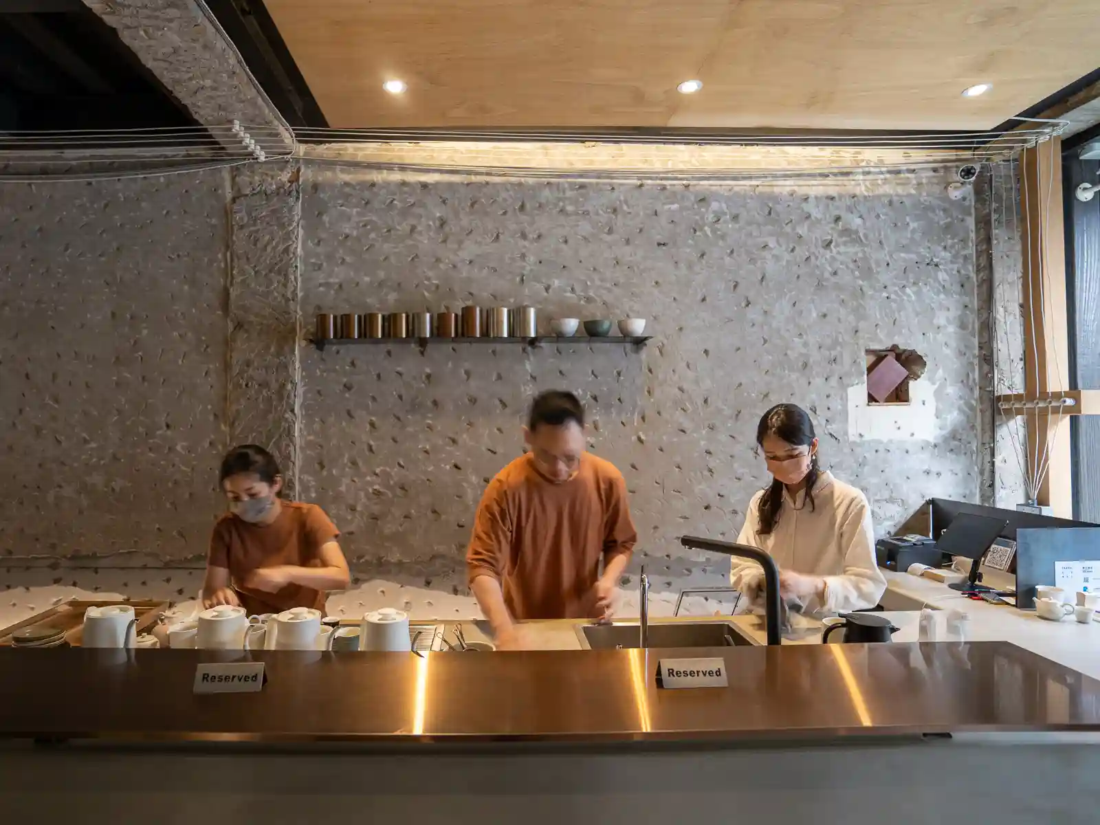 Three employees are busy behind the minimalist bar at Zhao Zhao Tea Lounge.