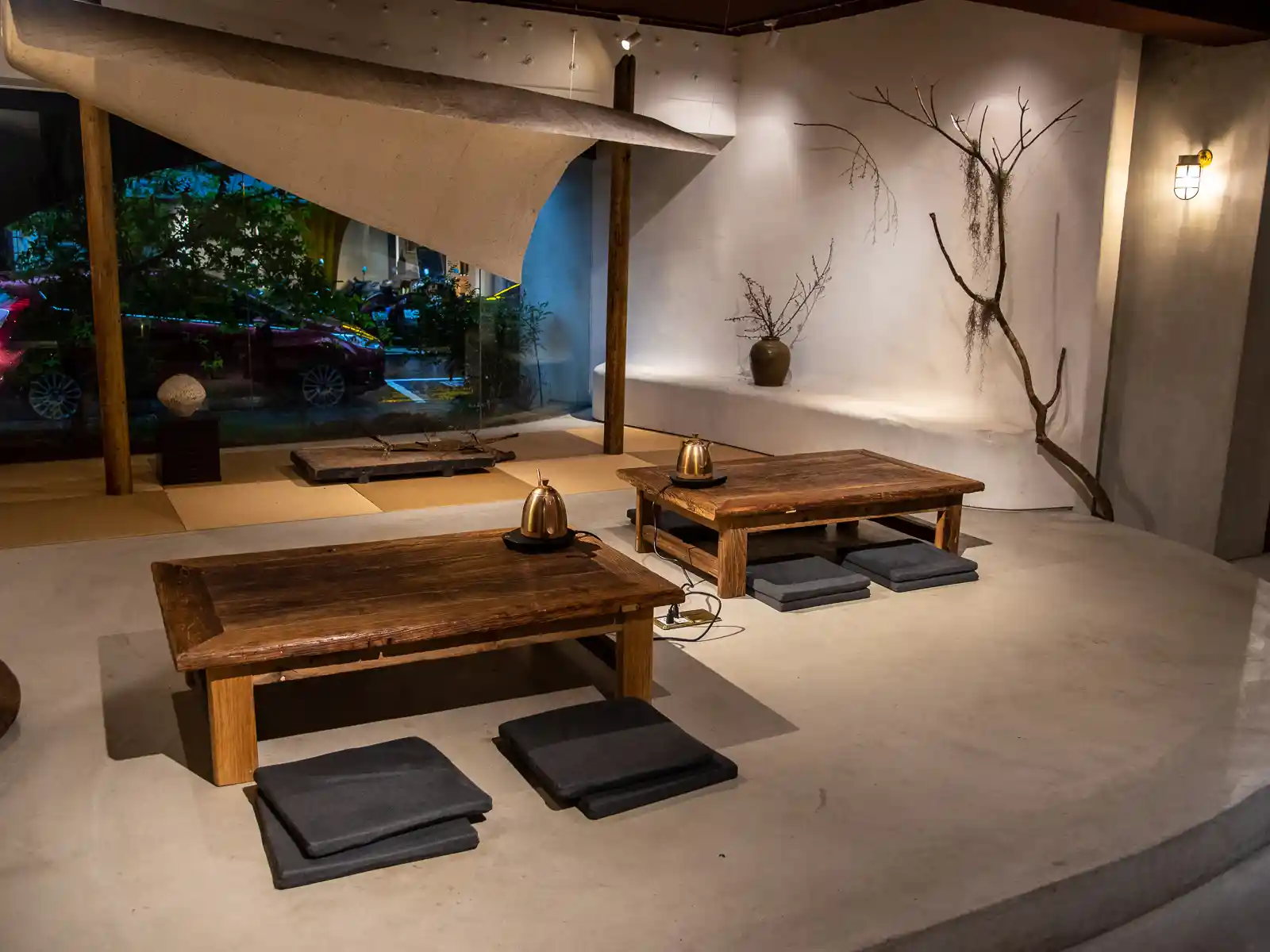 Wooden tables and cushions as well as installation art at Hermit's Hut tatami-seating area.