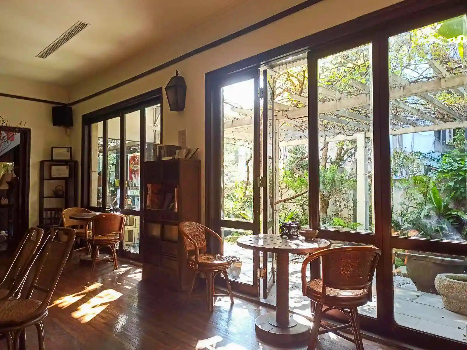 Sunlight shines through floor-to-ceiling windows illuminating one tea room in Wistaria Tea House.