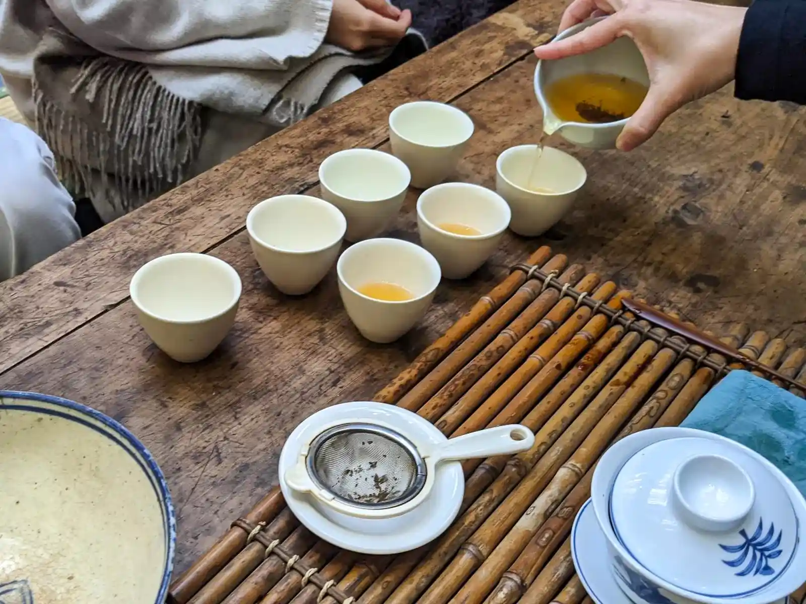 Tea is being poured from a tea serving pot into smaller tea cups.