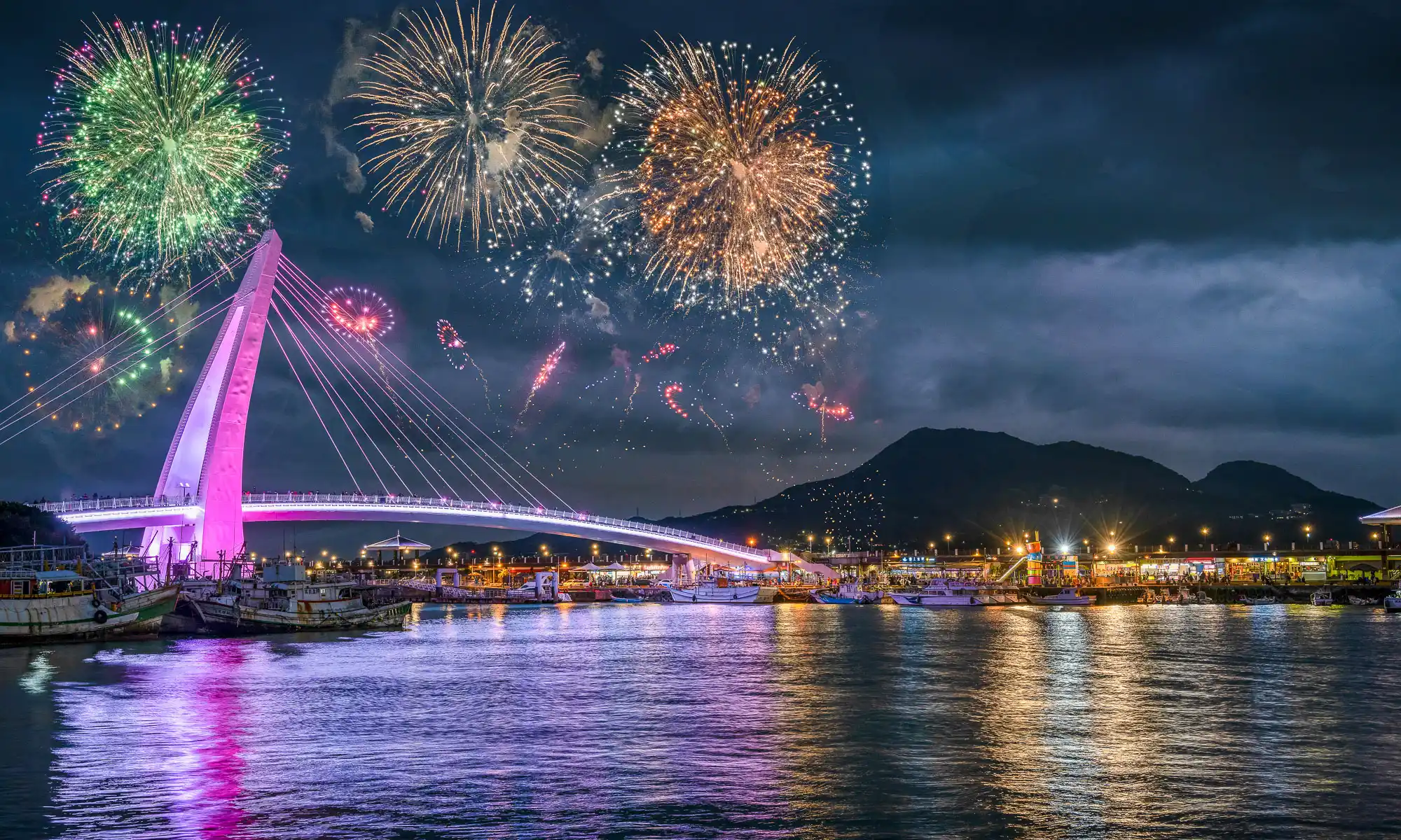 Fireworks explode over Tamsui Lover's Bridge in the evening.