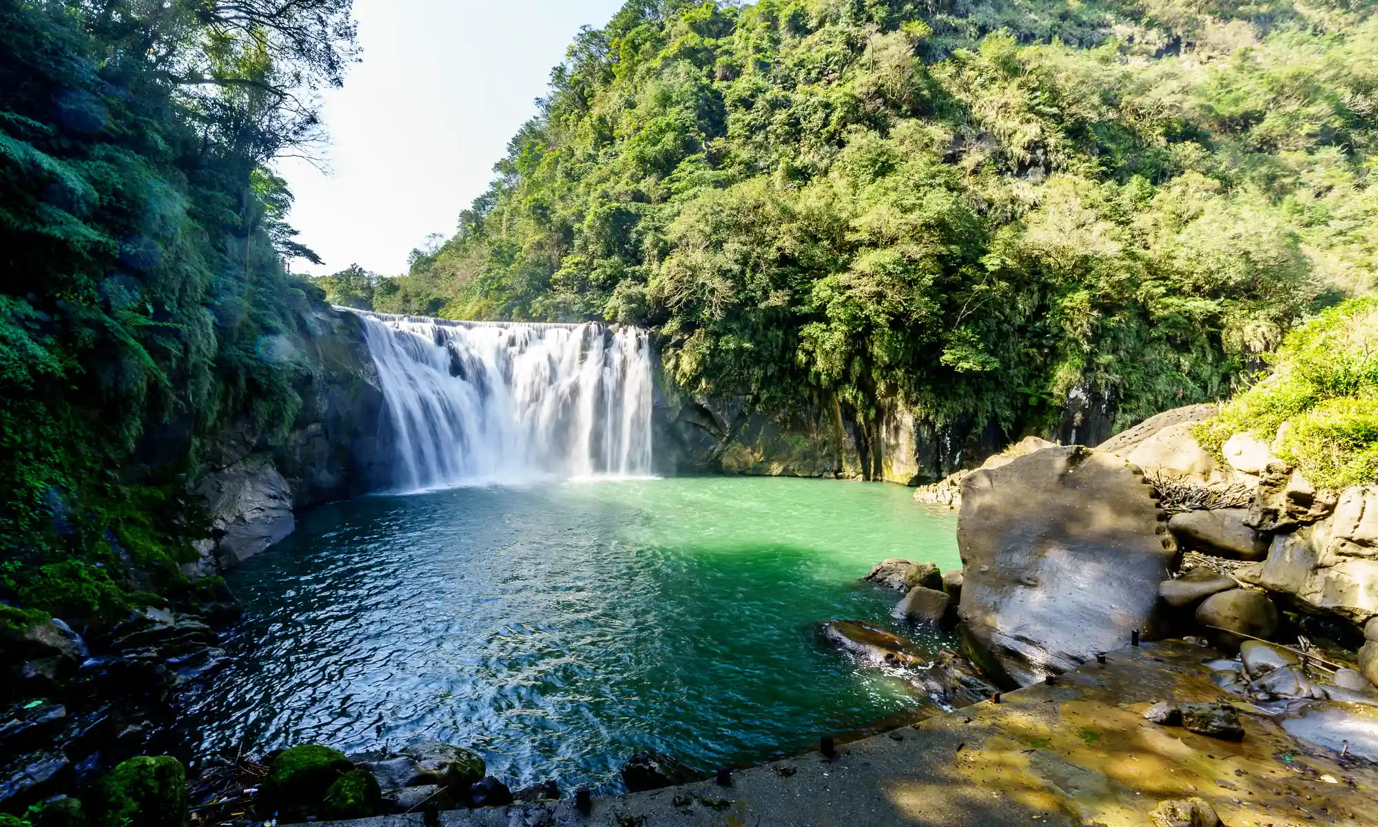 The horseshoe-shaped Shifen Waterfall plummets into a deep green bowl-shaped pool.