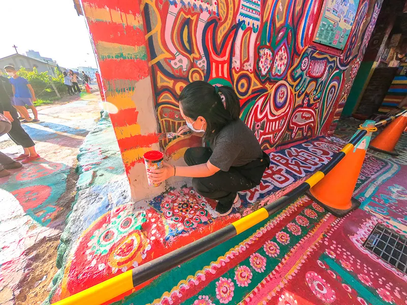 A local artist helps to touch-up one of the murals within Taichung's Rainbow Village.
