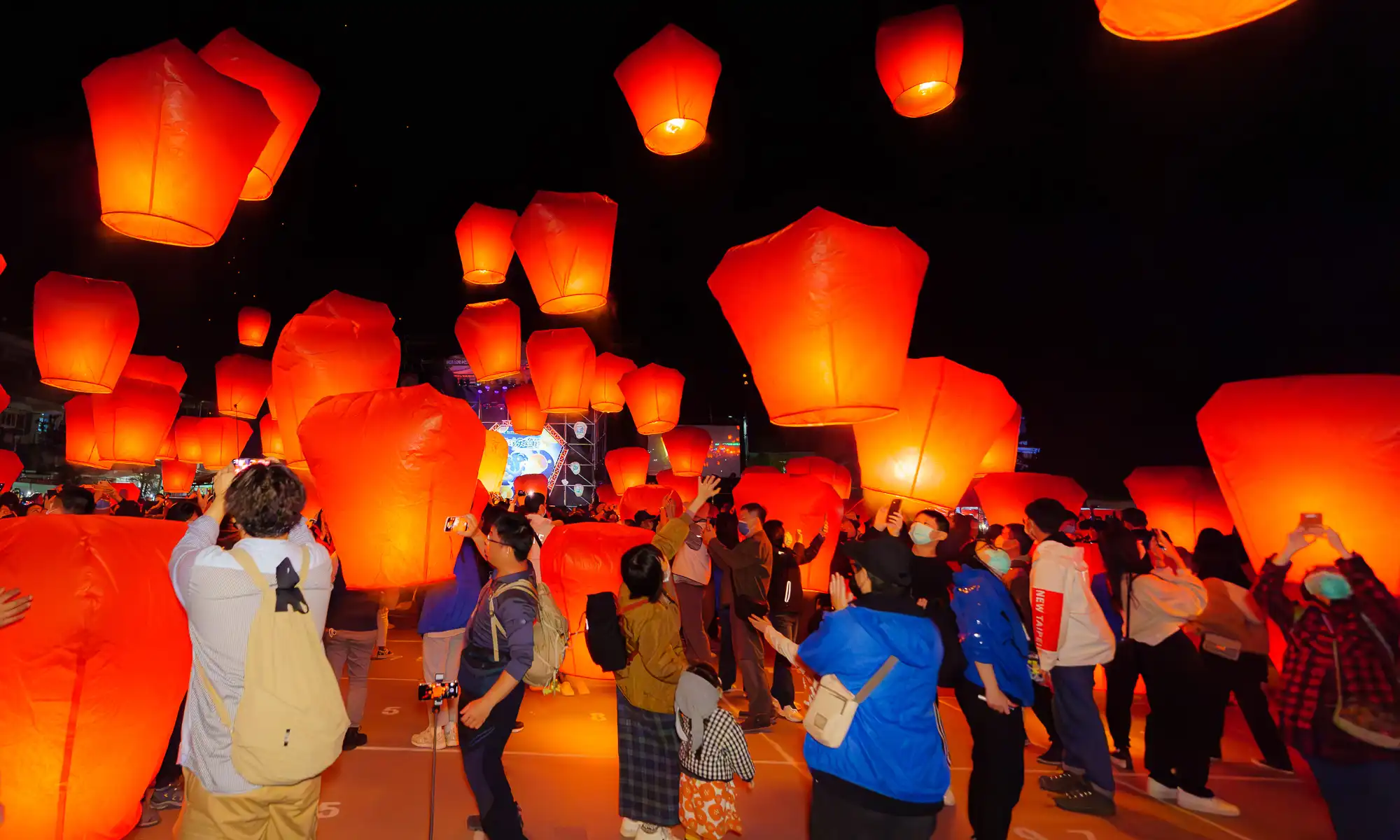 Dozens of red lanterns that are the size of small refrigerators are simultaneously released into the night sky.