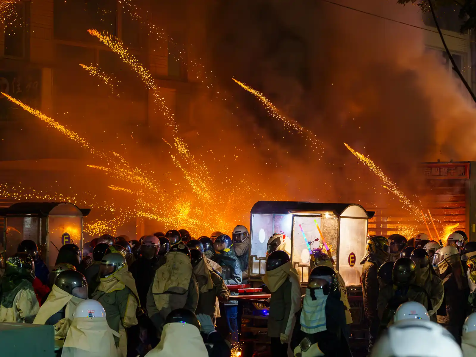 A barrage of beehive-style fireworks erupts from behind a palanquin.