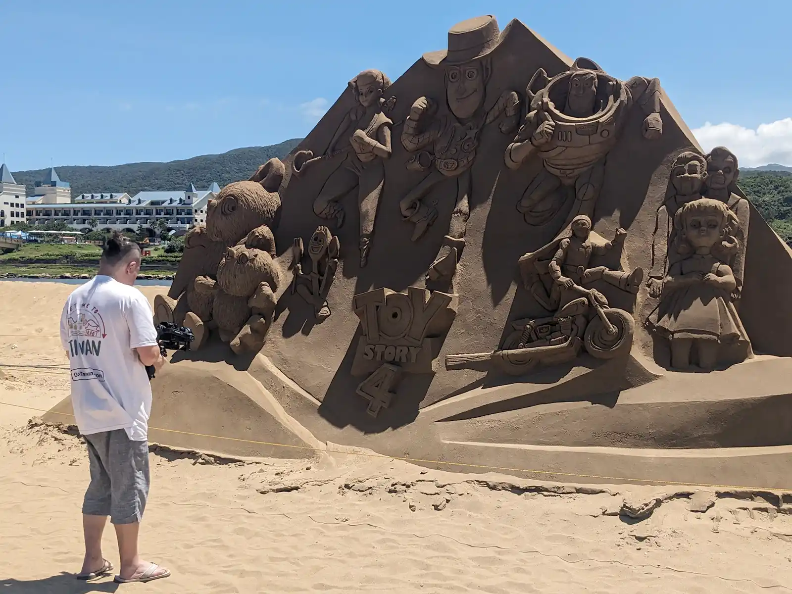 Photographer is taking photo of a disney theme sand sculpture.