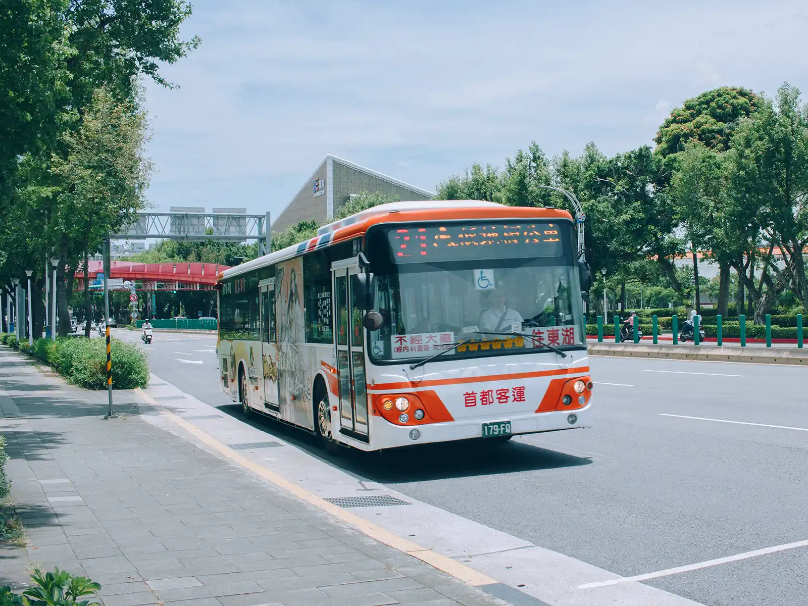 A bus approaches a bus stop on the side of the road.