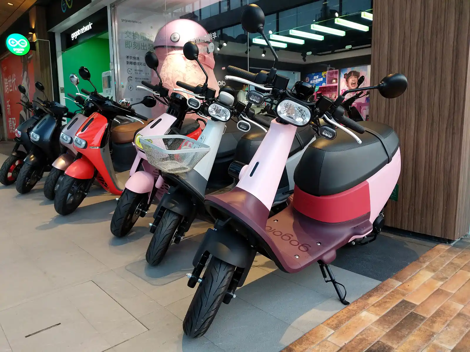 A line of colorful electric scooters parked outside a shop in Taiwan.