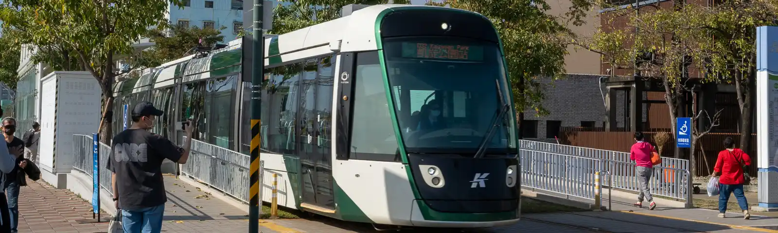 A light rail train slows at a pedestrian crossing Pier 2 Art Center Station.