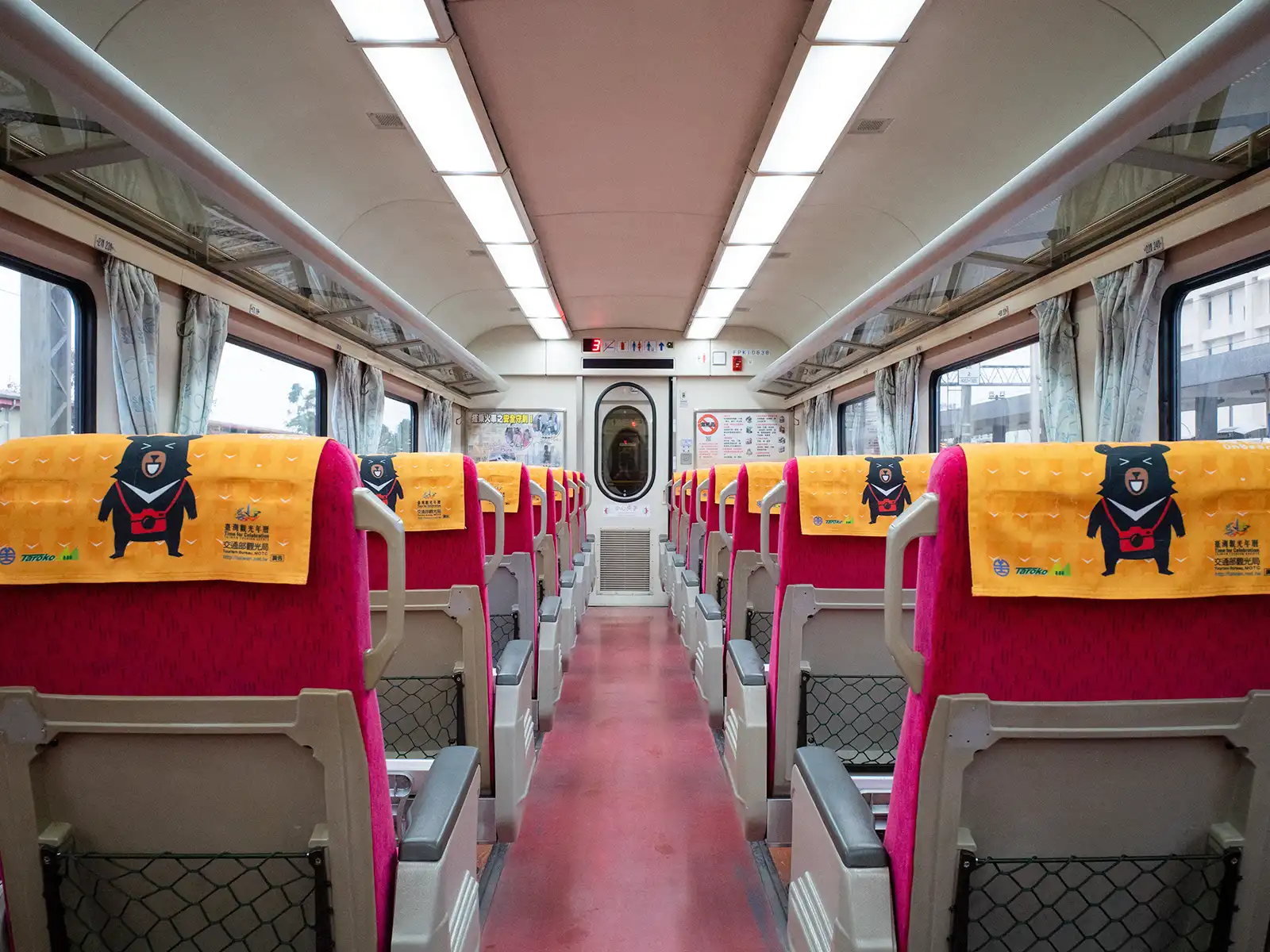 The interior of a train cabin features two rows of seats on either side of the aisle.