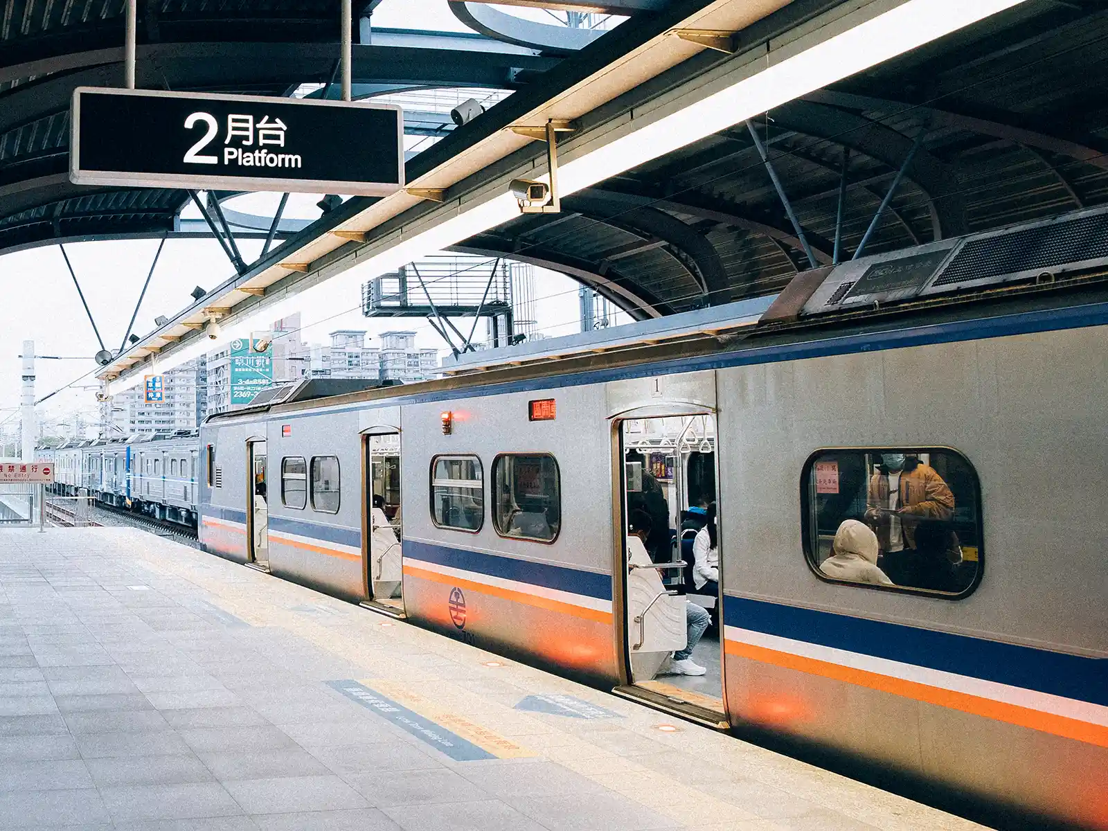 A train with its doors open waiting for passengers to board on a platform.